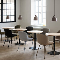 Modern seating in neutral tones with black and beige chairs against light wooden floors and soft pendant lighting.