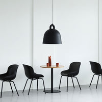 Black pendant lamp with smooth finish, surrounded by sleek black chairs and a minimalist round wooden table.