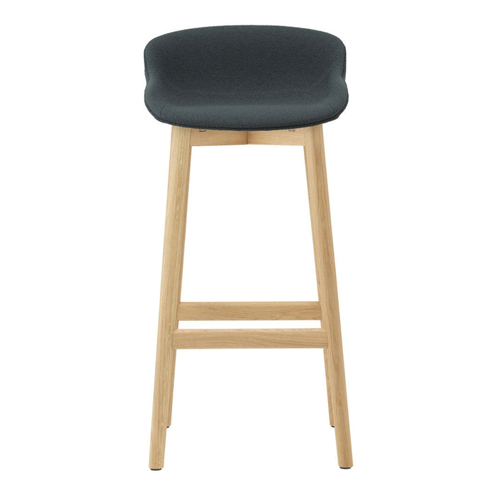 Dark gray upholstered stool with smooth contours and natural wood legs, featuring a minimalist design.