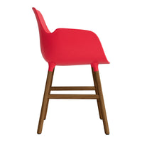 Bright red chair with smooth curves and a wooden base, perfect for modern decor.