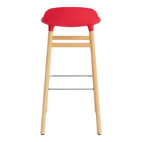 Red padded stool with natural wood legs and a sleek metal footrest, perfect for modern spaces.