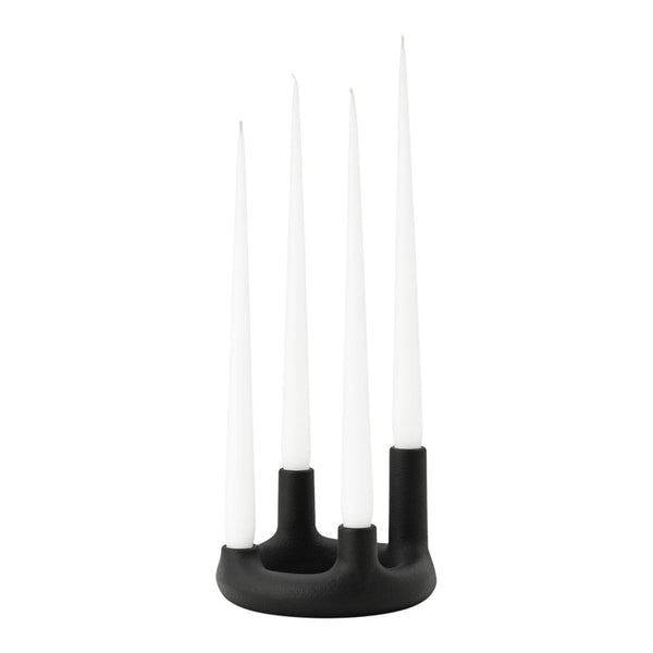 Black candle holder with four long white candles, creating a modern, minimalist design.