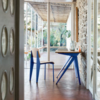 Blue chair and table set against a natural stone wall, featuring a modern design and warm wooden tones.