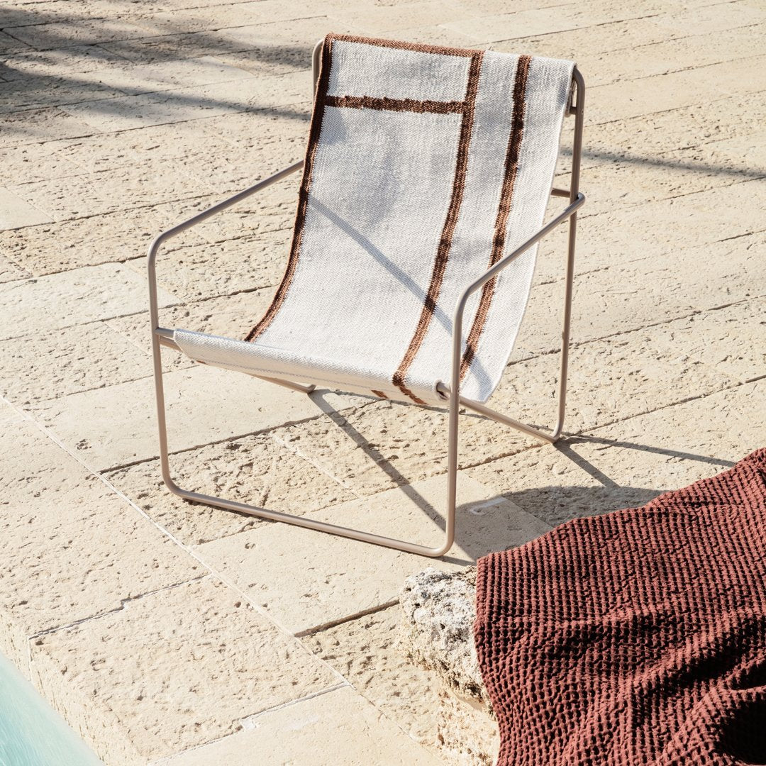 Stylish armchair featuring a beige and brown striped pattern, perfect for outdoor relaxation by the pool.