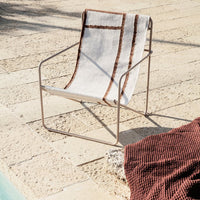 Stylish armchair featuring a beige and brown striped pattern, perfect for outdoor relaxation by the pool.