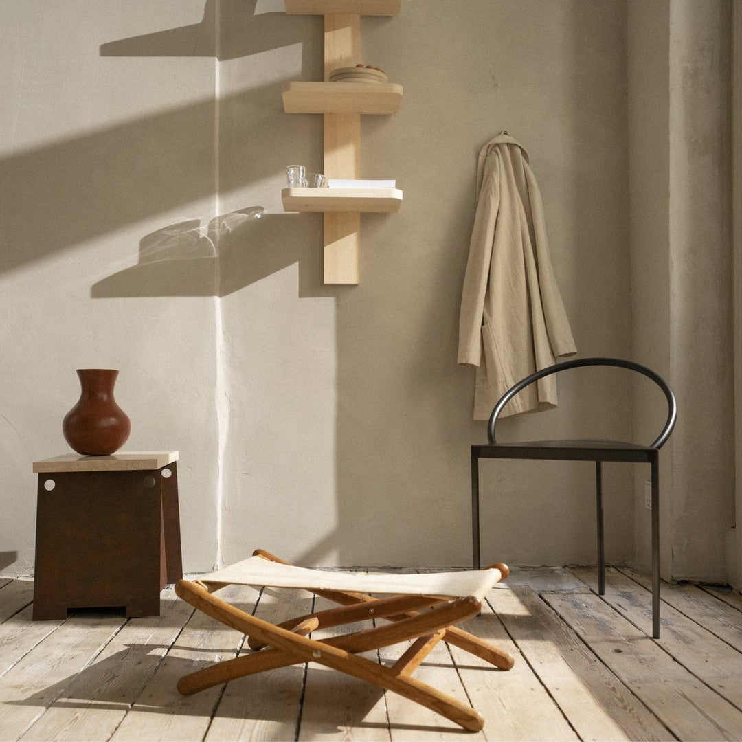 "Neutral-toned room with wooden textures, a cream fabric stool, black chair, and earthy brown vase."