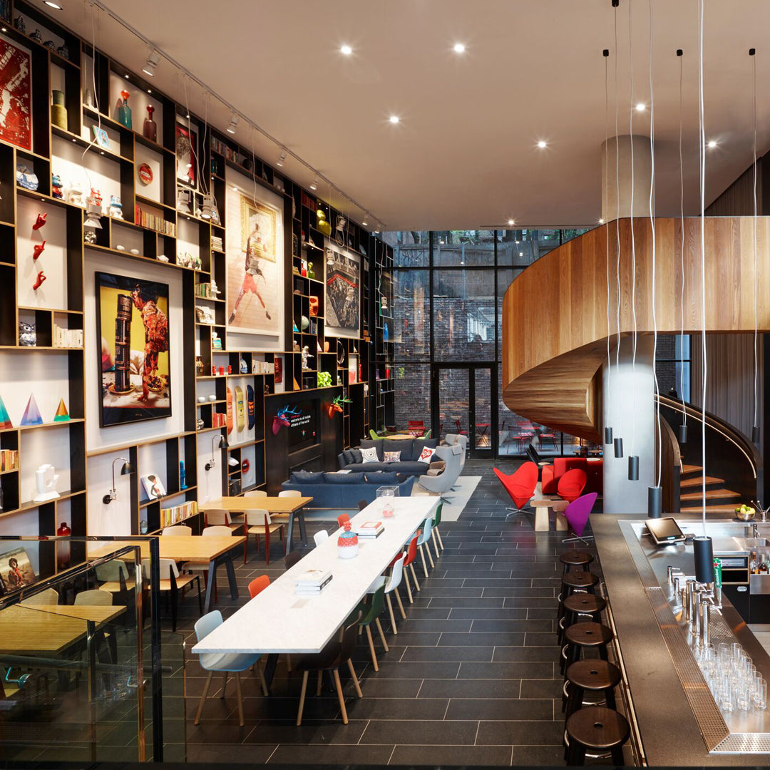 Modern interior with vibrant art, wooden accents, and a sleek black floor, featuring colorful chairs and a spiral staircase.