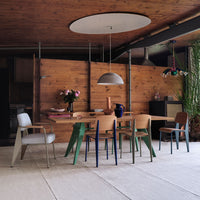Modern dining room featuring a wooden table with multicolored chairs in green, blue, and natural wood tones.
