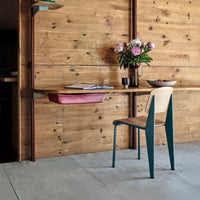 "Rustic wood wall, sleek green chair, soft pink bowl, and vibrant floral arrangement against a neutral floor."