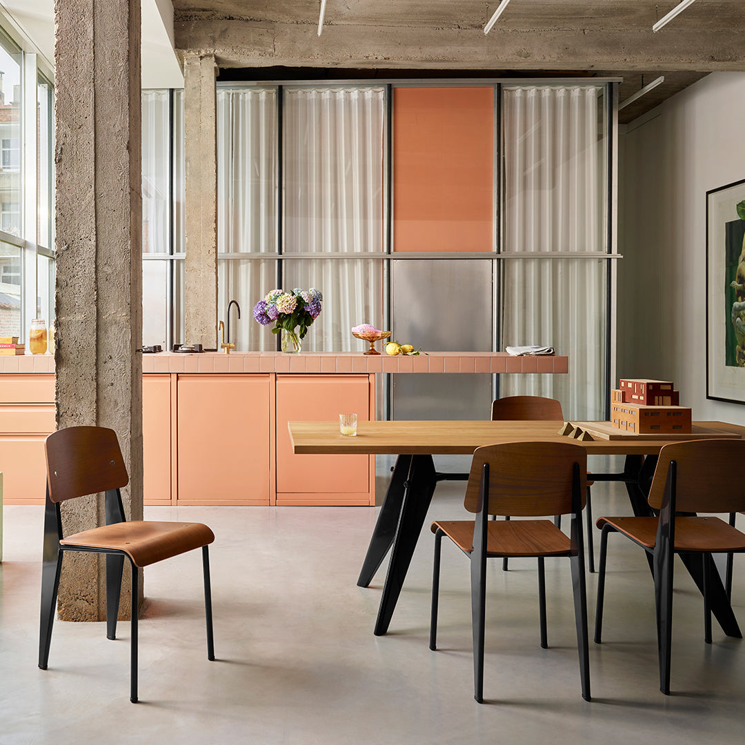 Modern kitchen featuring peach cabinets, sleek black chairs, and a light wood dining table in a contemporary setting.