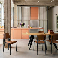 Modern kitchen featuring peach cabinets, sleek black chairs, and a light wood dining table in a contemporary setting.