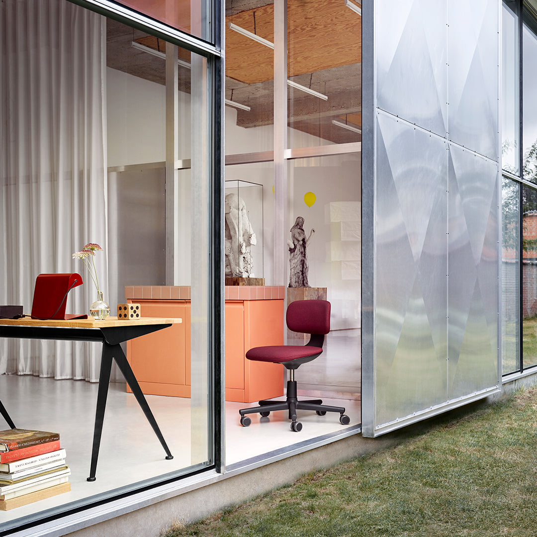Modern workspace featuring a burgundy office chair, sleek black desk, and soft white and peach tones in interior decor.