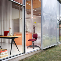 Modern workspace featuring a burgundy office chair, sleek black desk, and soft white and peach tones in interior decor.