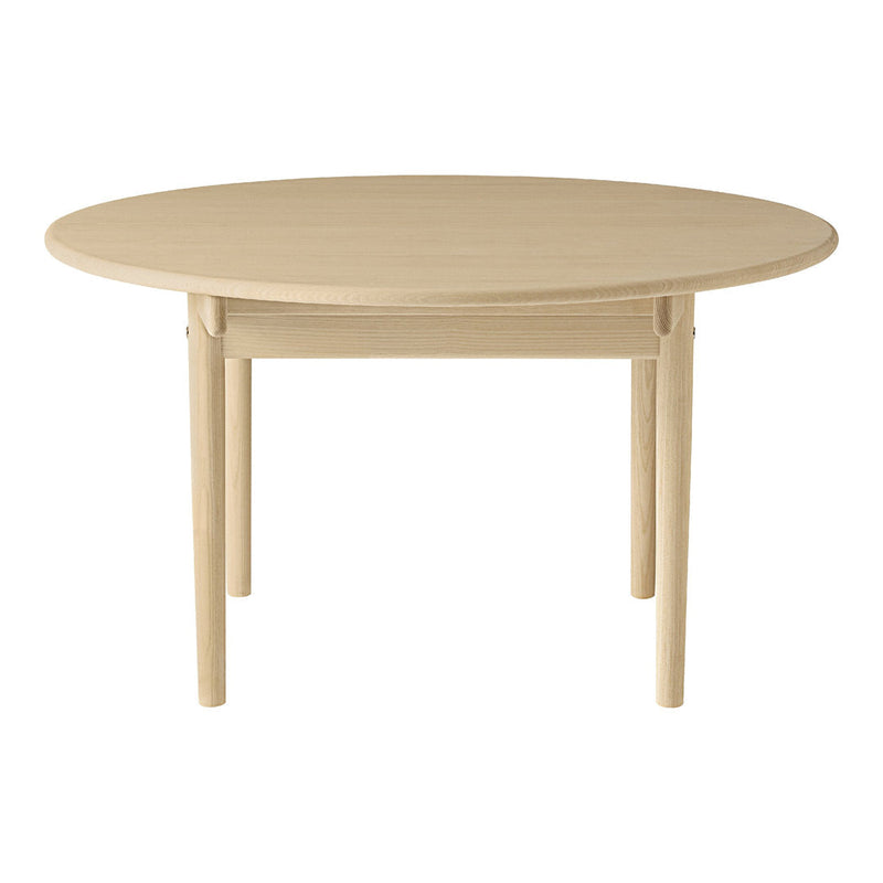 Round wooden table in a light beige finish with a smooth, minimalist design. Perfect for modern dining spaces.