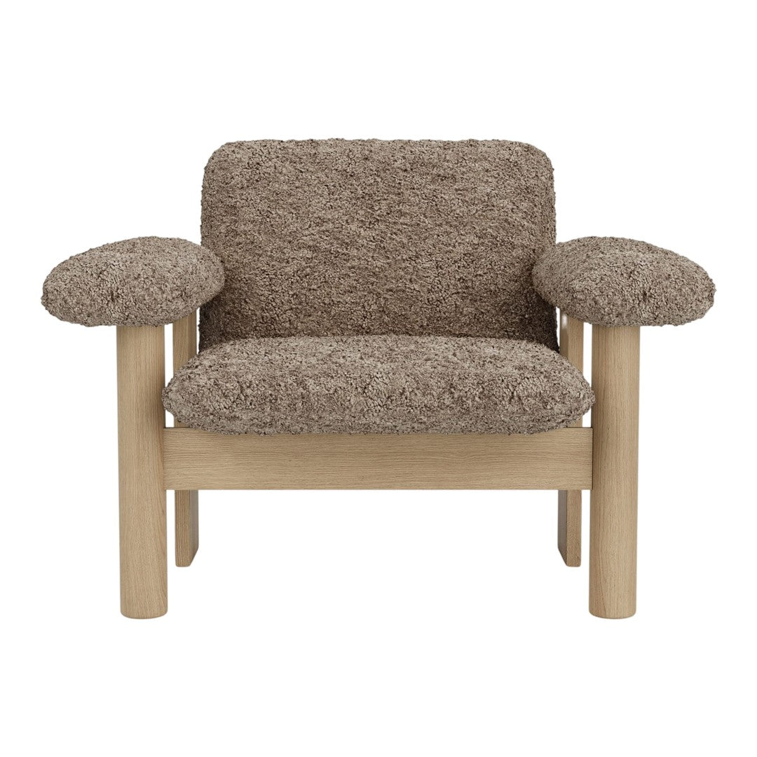 Brown textured upholstery armchair with light wooden legs and rounded armrests. Stylish and modern design.