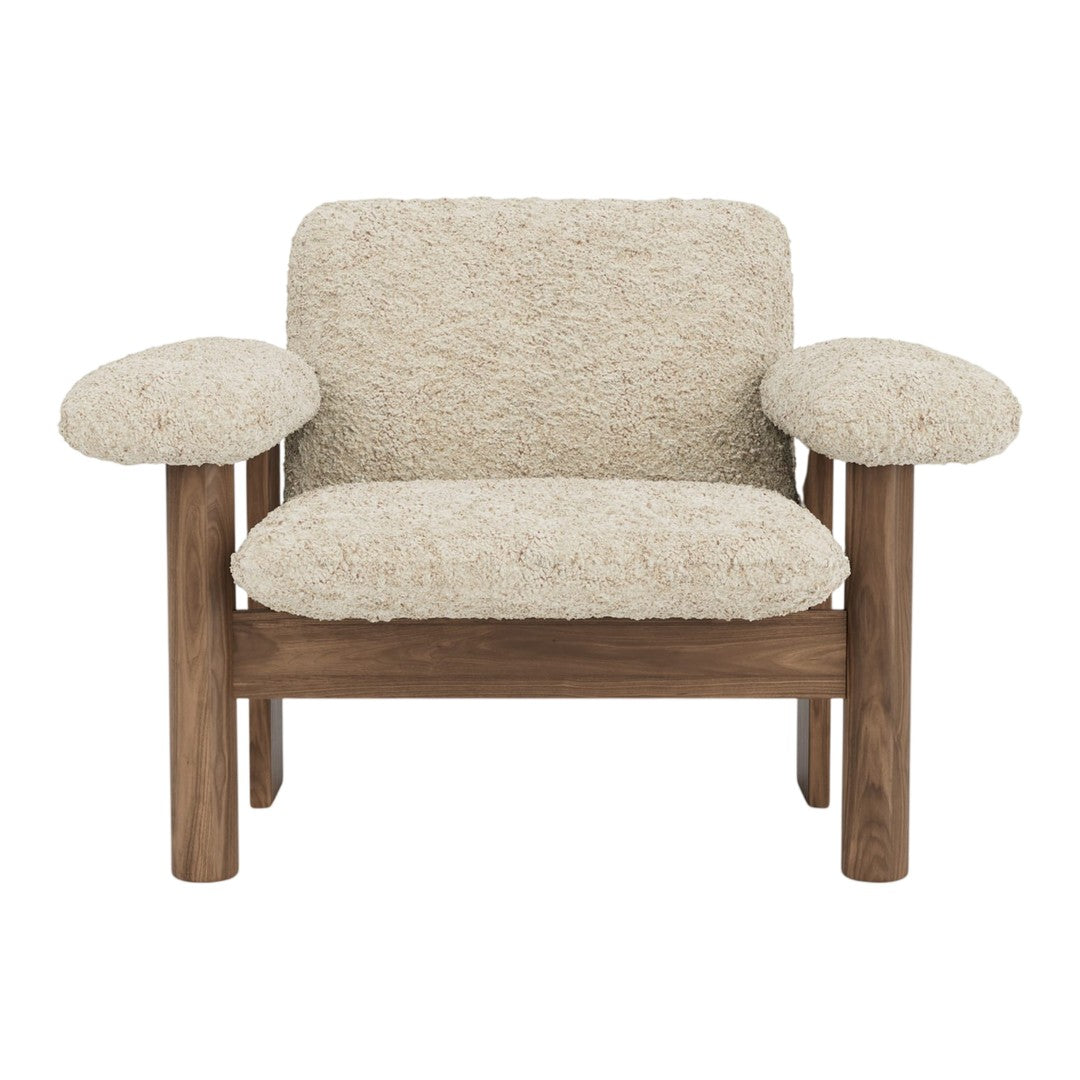 Beige textured upholstery with plush, rounded armrests and warm wooden frame. Cozy, modern accent chair design.