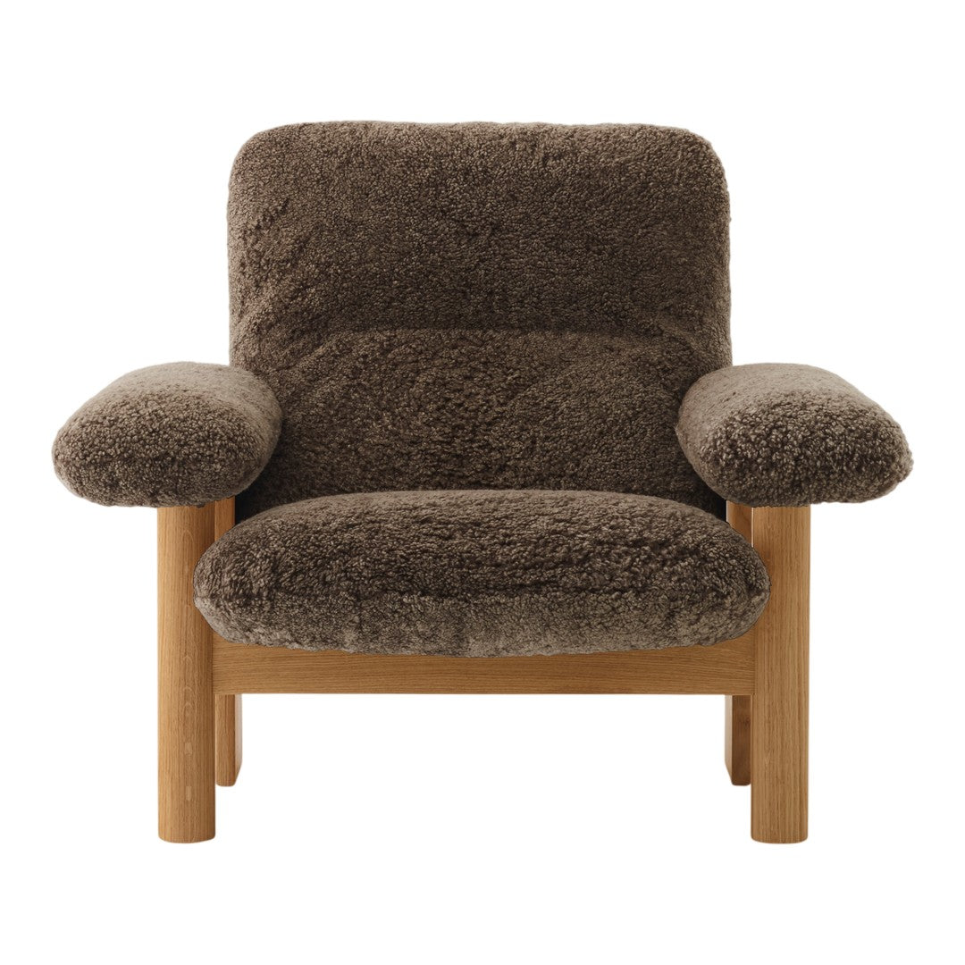 Brown textured armchair with plush fabric and wooden frame, featuring soft, rounded armrests for comfort.
