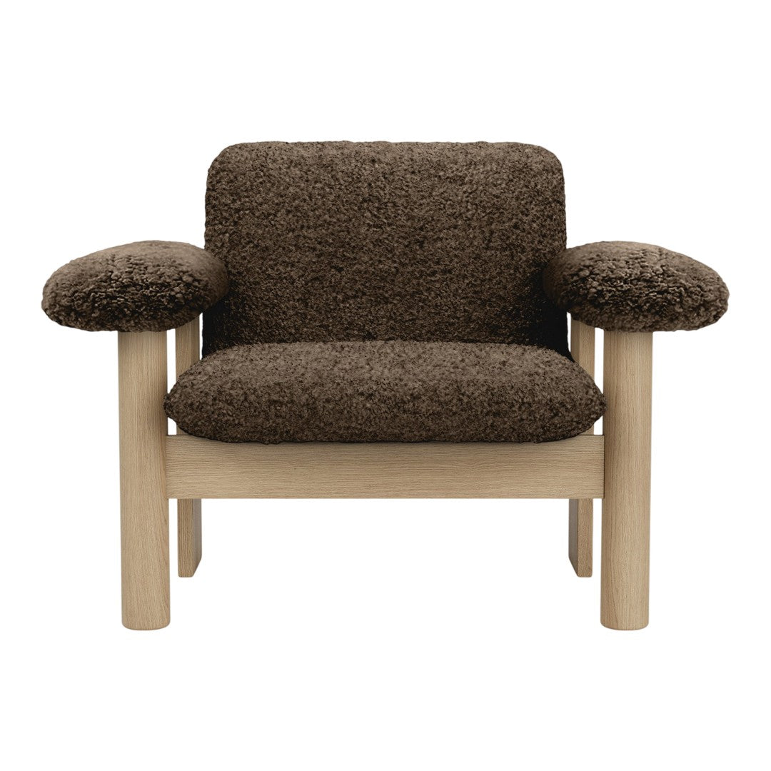 "Cozy brown faux fur armchair with soft rounded arms and light wood legs, ideal for modern living spaces."
