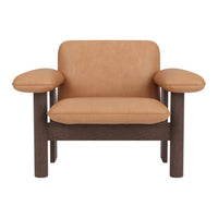 Tan leather armchair with a dark wood frame, featuring minimalist design and soft curves. Ideal for modern decor.