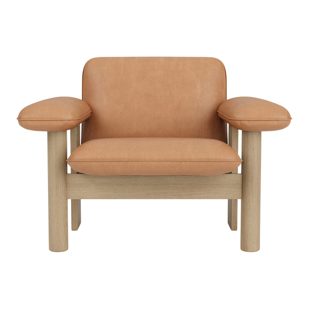 Tan leather armchair with round, soft cushions and a light wood frame. Modern, minimalist design with clean lines.