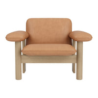 Tan leather armchair with round, soft cushions and a light wood frame. Modern, minimalist design with clean lines.
