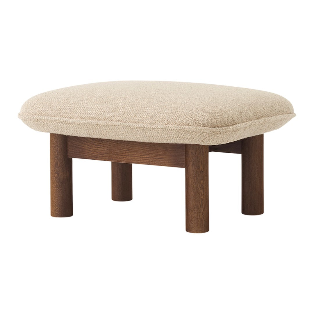 Beige upholstered stool with a smooth surface and four dark wooden legs, showcasing a minimalist design.
