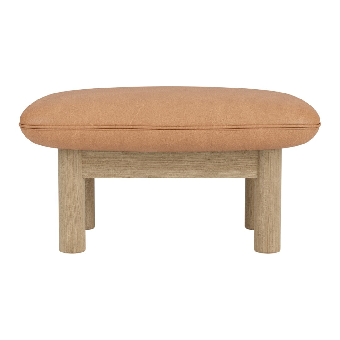 Tan leather ottoman with a smooth, rounded top and light wooden legs, featuring a minimalist design.