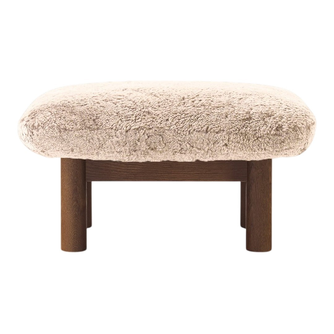 Light beige plush ottoman with fluffy texture and dark wooden legs. Cozy, modern design with minimalistic appeal.