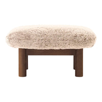 Light beige plush ottoman with fluffy texture and dark wooden legs. Cozy, modern design with minimalistic appeal.