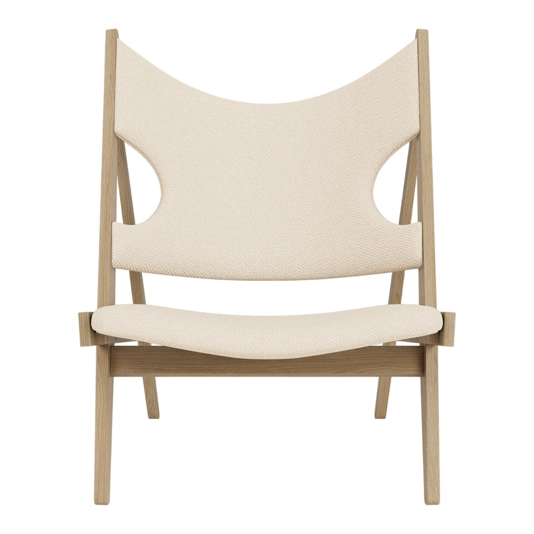 Minimalist cream chair with a unique cut-out design, featuring light wooden legs and a smooth fabric finish.