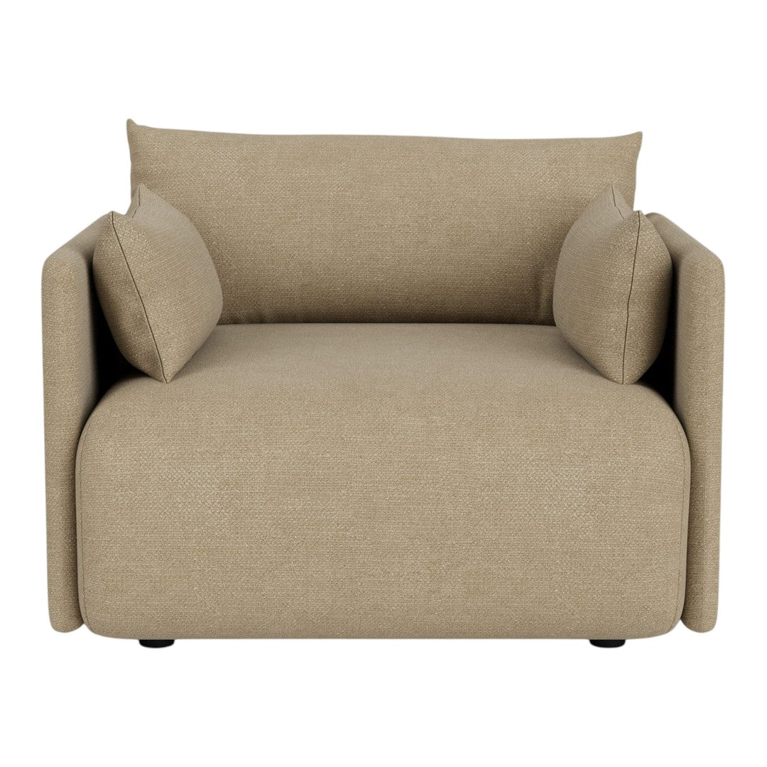 Beige armchair with minimalist design and soft, inviting texture, featuring two plush accent pillows.