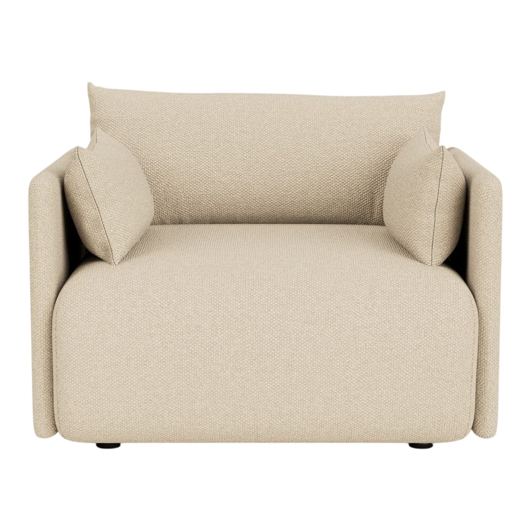 Beige armchair with soft textures and minimalist design, featuring two matching cushions for added comfort.