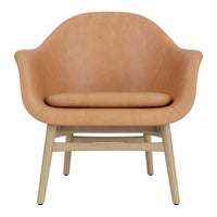 Tan leather armchair with smooth curves and a light wood base, perfect for modern decor. 