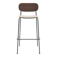 Brown wooden backrest, cream seat, and sleek black metal legs create a modern, minimalist bar stool design.