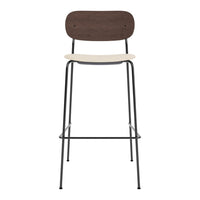 Brown wooden backrest and cream seat on a sleek black metal frame barstool. Minimalist design.