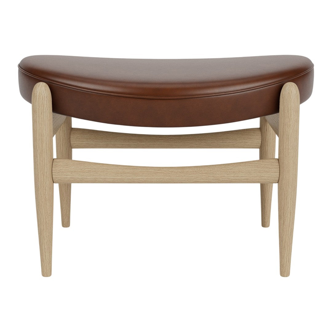 Brown curved leather upholstered ottoman with light wood legs, featuring a minimalist design and subtle natural textures.