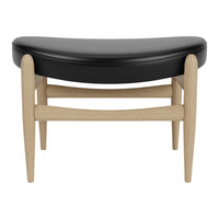Black curved cushion with light wood legs, featuring a minimalist design for modern decor.