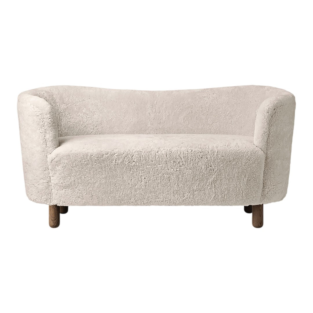 Cozy off-white upholstered sofa with soft, textured fabric and rounded design, featuring wooden legs.