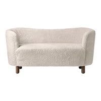 Cozy off-white upholstered sofa with soft, textured fabric and rounded design, featuring wooden legs.