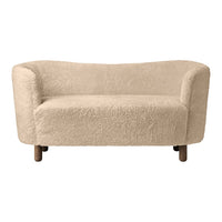 Beige curved sofa with soft, textured fabric and natural wood legs, perfect for cozy living spaces.