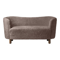 Soft, light brown sofa with a textured, fluffy fabric and rounded shape, featuring natural wooden legs.