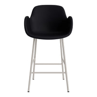 Black padded stool with sleek white metal legs, featuring a minimalist design and smooth surface. Perfect for modern decor.