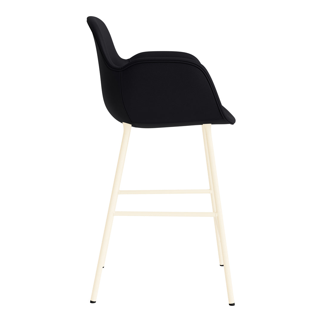 Black upholstered bar stool with a smooth finish and light wooden legs. Minimalist design with a modern aesthetic.