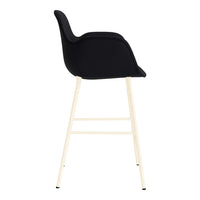 Black upholstered bar stool with a smooth finish and light wooden legs. Minimalist design with a modern aesthetic.