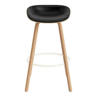 Black padded seat bar stool with natural wood legs and white footrest. Modern design for stylish interiors.