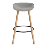 Gray upholstered bar stool with natural wood legs and a black metal footrest, showcasing a modern minimalist design.