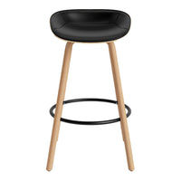 Black padded seat bar stool with natural wooden legs and a sleek black footrest, featuring a modern minimalist design.