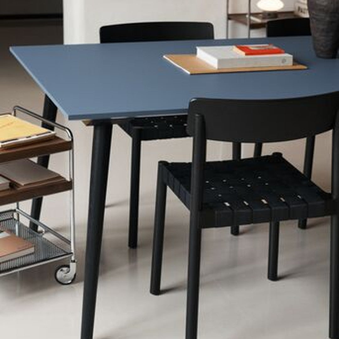 "Modern black and blue dining table with woven black chairs, showcasing sleek lines and minimalist design."