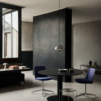 Modern dining area featuring deep blue chairs and a sleek black table against a neutral-toned backdrop.
