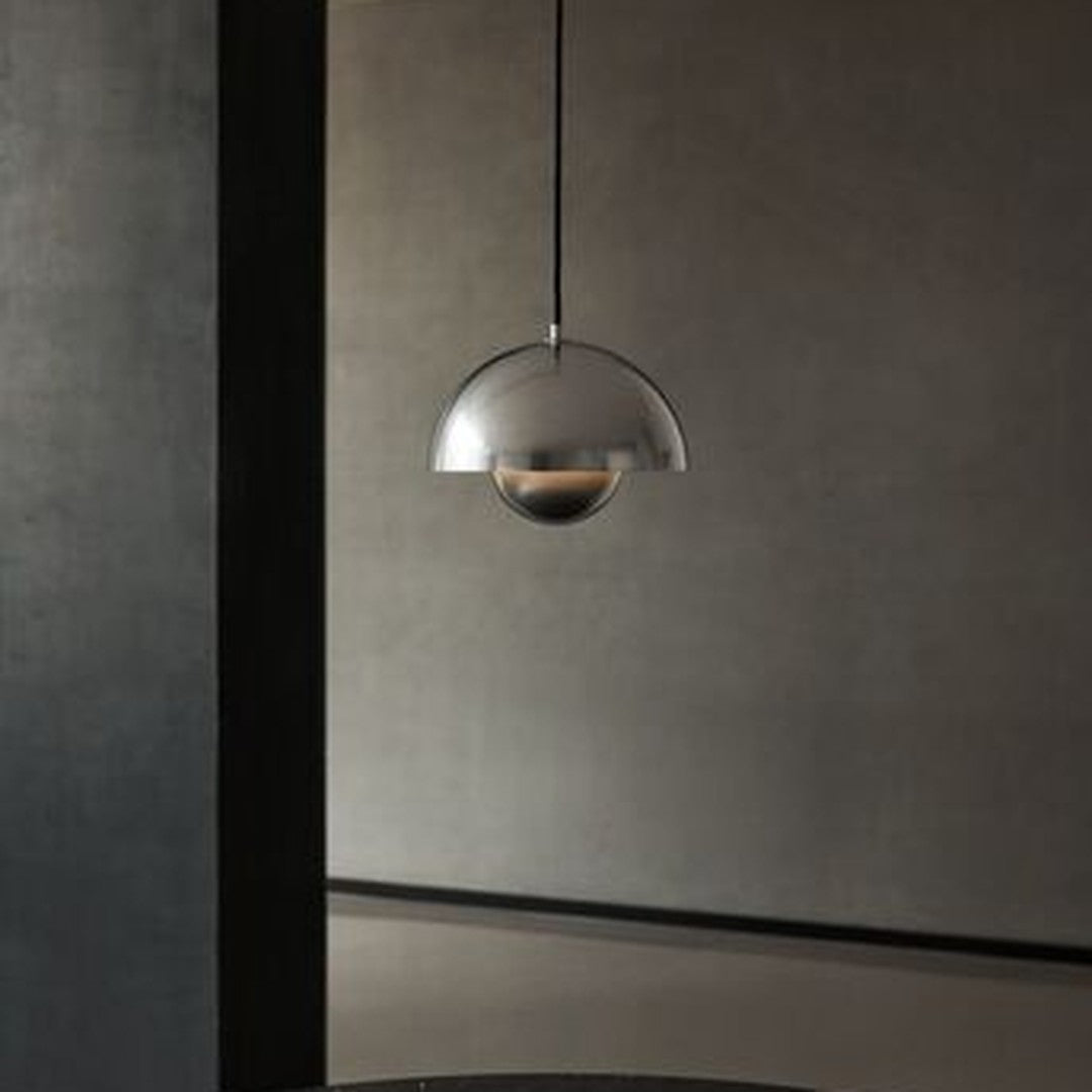 Sleek silver pendant lamp with a half-sphere design, casting a warm glow against a matte dark background.